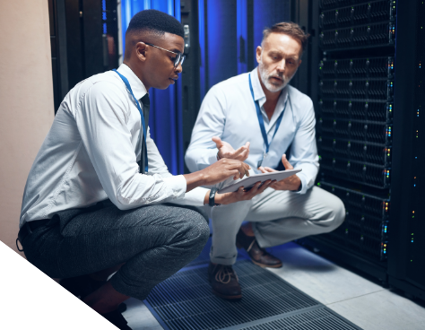 Two men working on a tablet in a server room